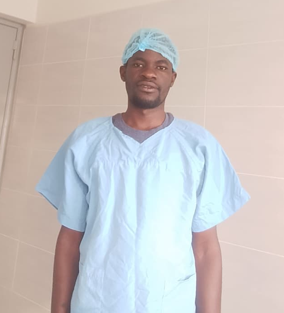 A healthcare worker in surgical scrubs and cap on a hospital ward