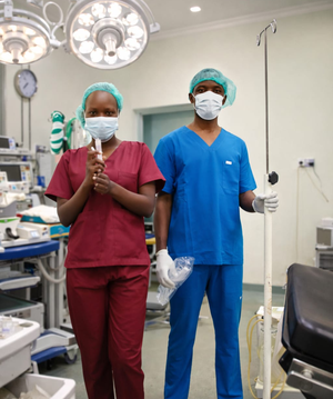 Two healthcare workers in scrubs preparing an operating theatre